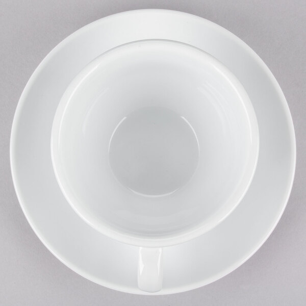 A CAC white cup and saucer on a white surface.