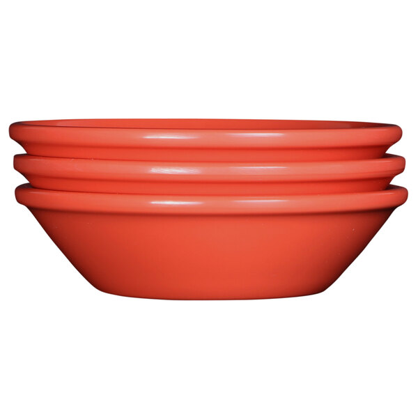 A stack of orange Elite Global Solutions Rio Spring Coral melamine monkey dishes.