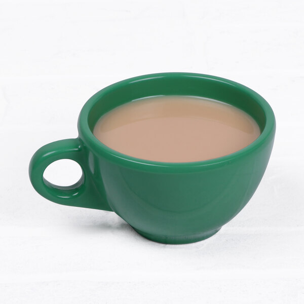 A close-up of a green Elite Global Solutions melamine coffee cup filled with brown liquid.