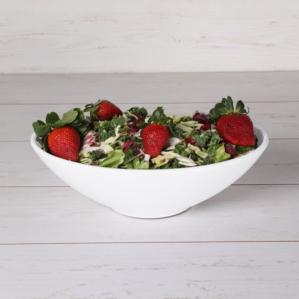 A white Elite Global Solutions Moderne oblong bowl filled with strawberries and kale salad.