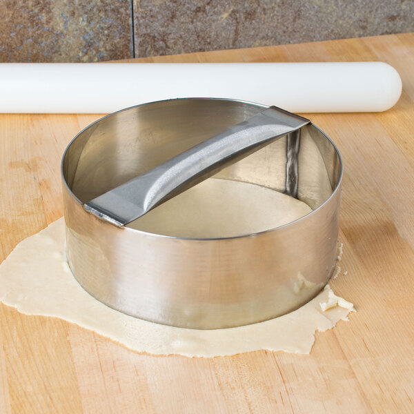 An American Metalcraft stainless steel dough cutting ring on a wooden surface.