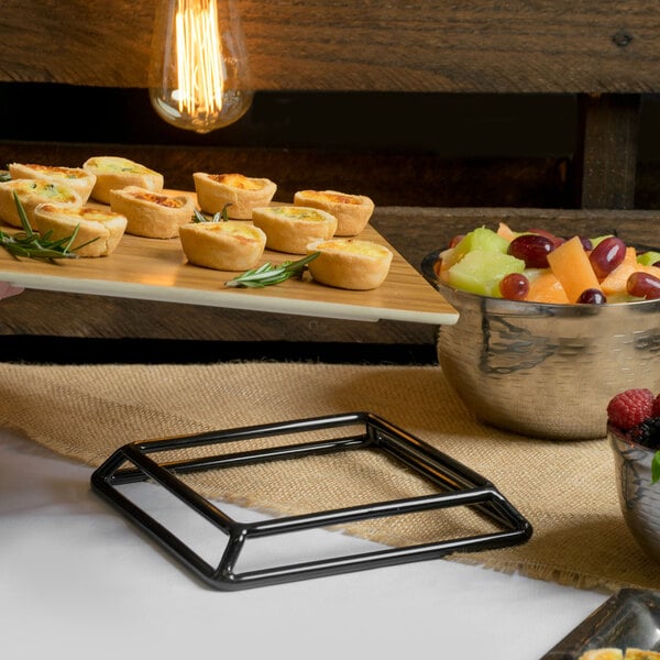 A person using an Elite Global Solutions rubber coated steel stand to carry a tray of food and a glass of wine.