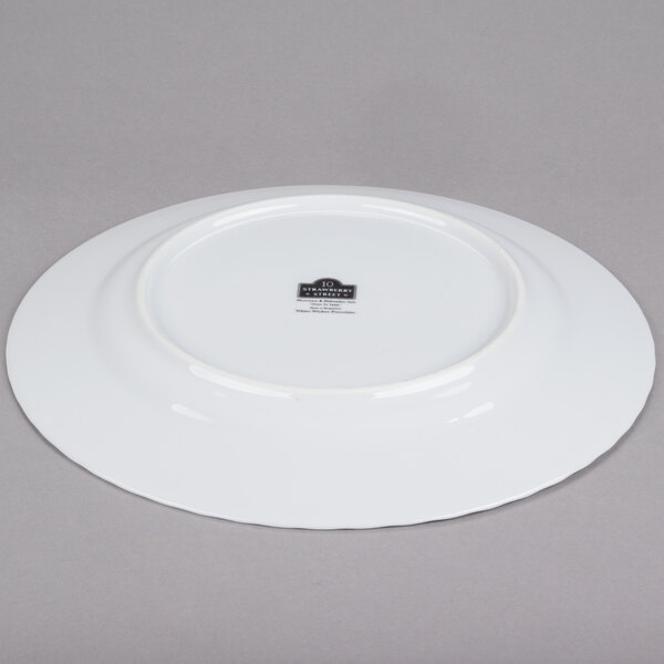 A white 10 Strawberry Street porcelain charger plate with a wicker design on the rim.