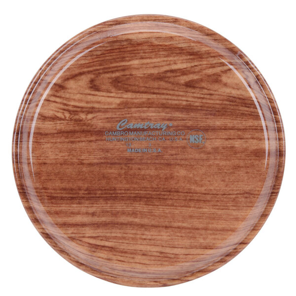 A round wooden Cambro tray with a logo on it.