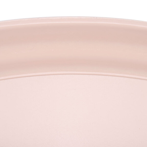 A close up of a light peach Cambro tray with an oval surface.