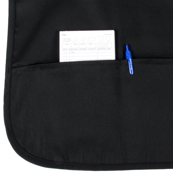 A black Chef Revival bib apron with a pen and a note pad in the pocket.