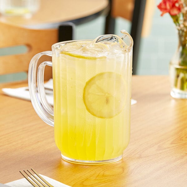 A clear pitcher of lemonade on a table.