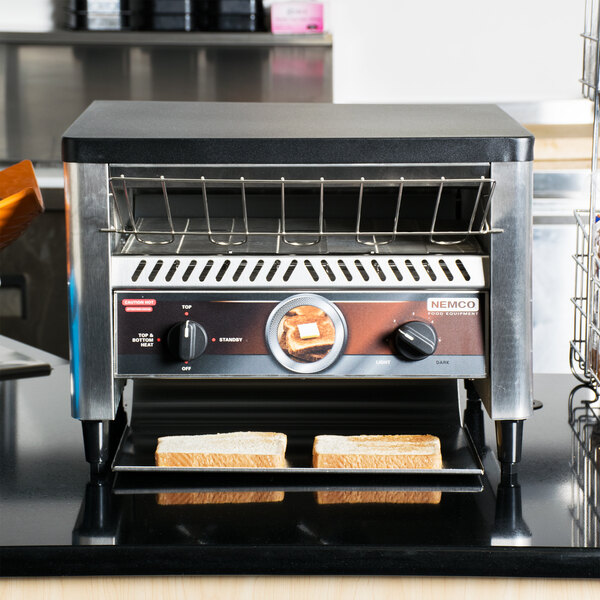A Nemco conveyor toaster with bread on it.