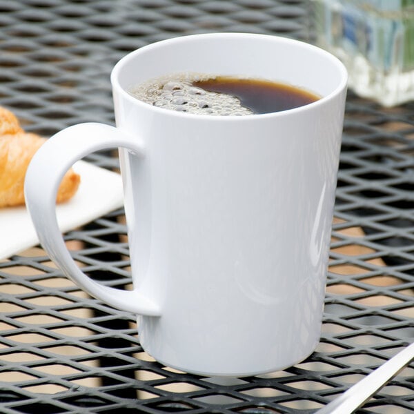 A white Carlisle Tritan mug filled with brown liquid on a table.