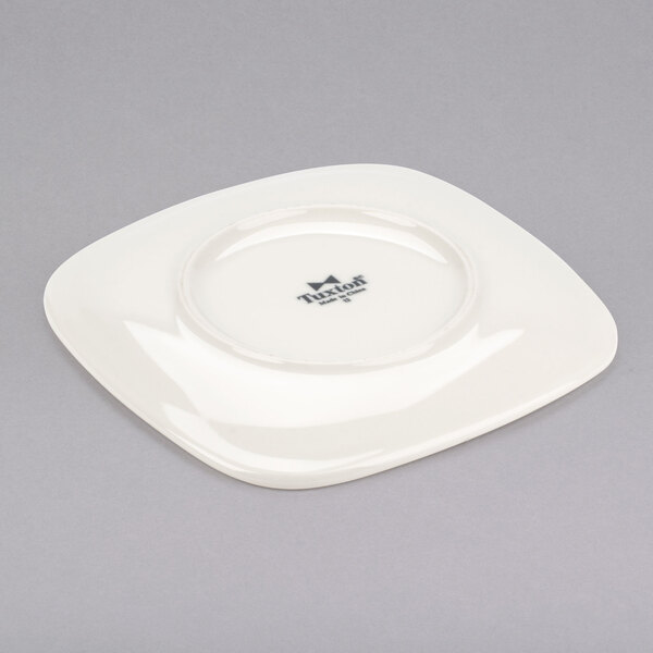 A white square Tuxton china plate with a logo on it.