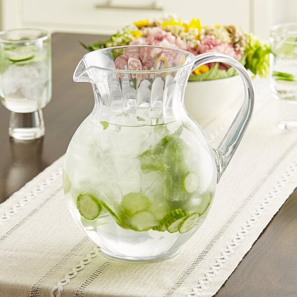 A clear GET Tahiti pitcher of water with ice and cucumber slices.