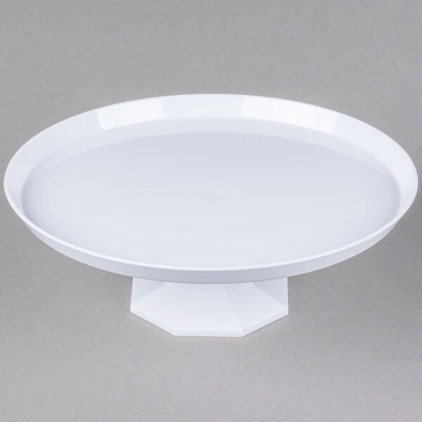 A white plate on a white pedestal stand.