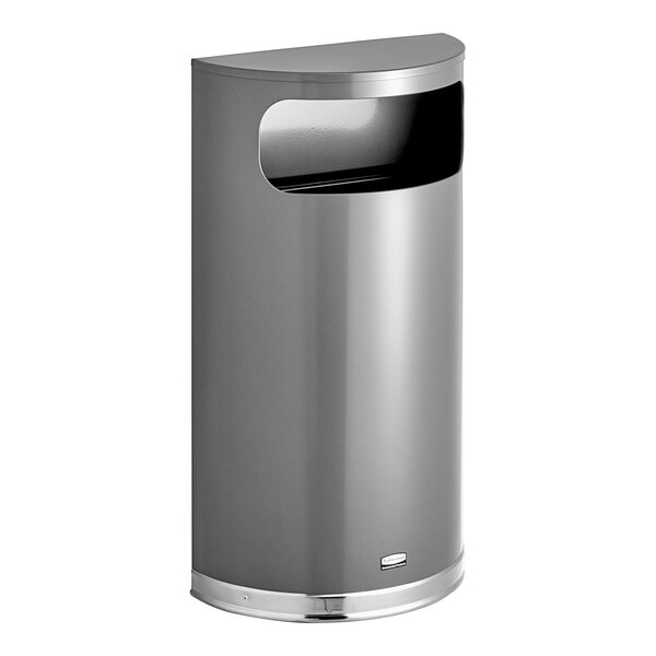A grey metal Rubbermaid half round trash can with chrome accents.