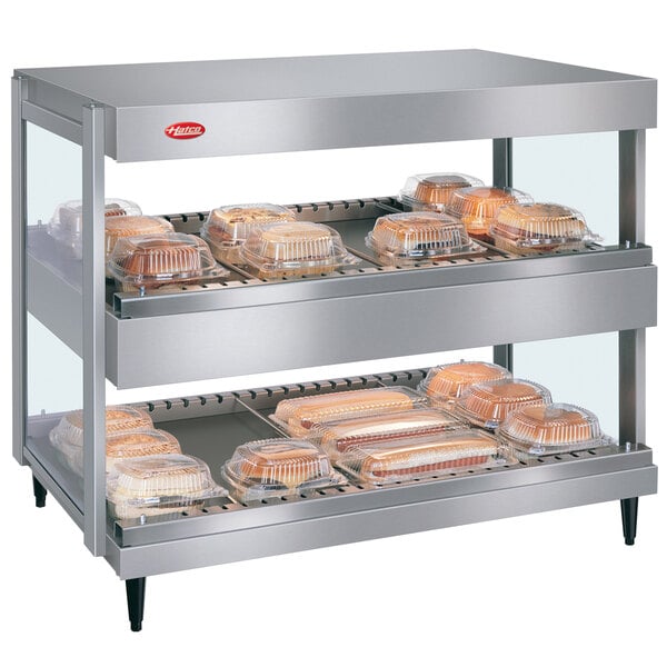 A Hatco countertop shelf with trays of food on a shelf.