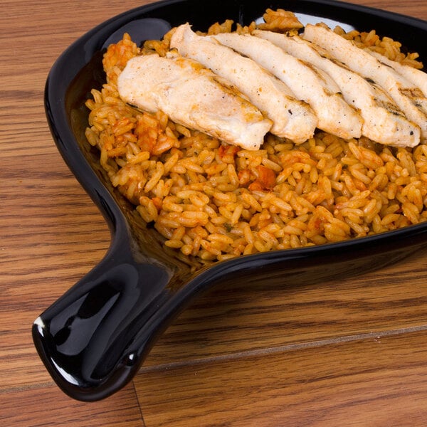 A CAC Festiware black fry pan plate with rice and chicken on it.