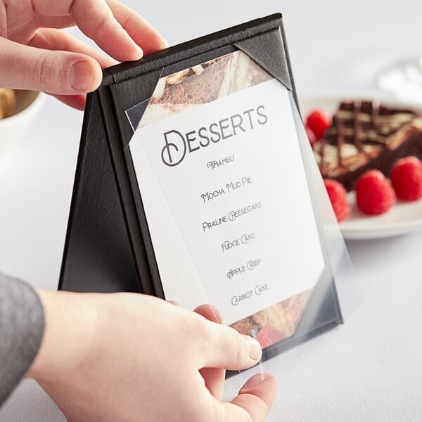 A hand holding a menu with a clear vinyl sheet protector inside.