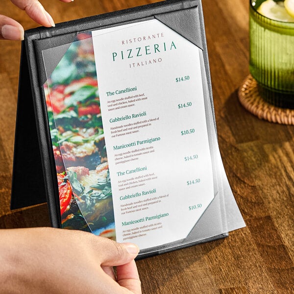 A hand holding a clear vinyl sheet protector with a menu inside.