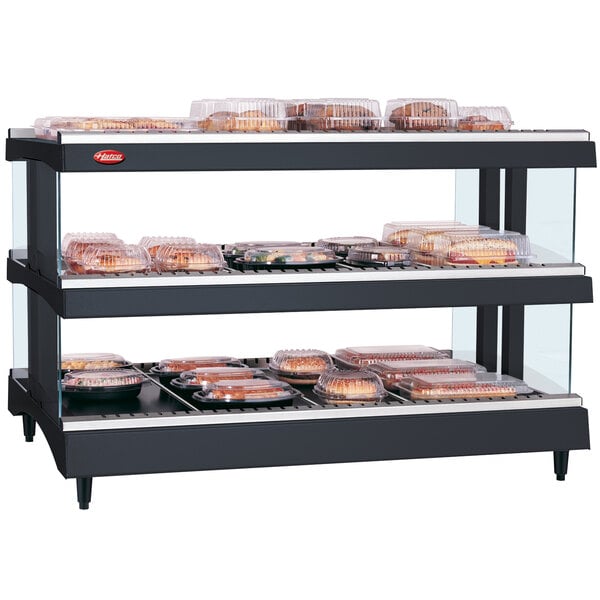 A Hatco countertop heated glass display with shelves of food on a counter.