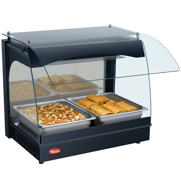 A Hatco countertop hot food display warmer with food in a glass-covered buffet.