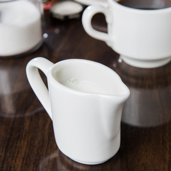 A white Tuxton China creamer on a table