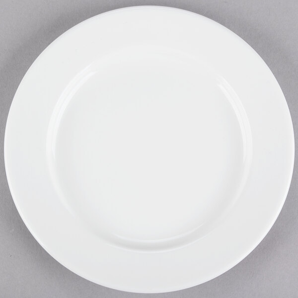 A Tuxton AlumaTux Pearl White china plate with a white rim on a gray surface.