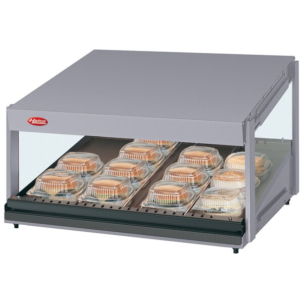 A Hatco countertop hot food display warmer with trays of food on a shelf in a bakery.