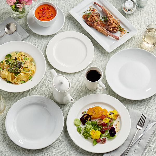 A table set with Tuxton AlumaTux china plates, bowls, and cups of food.