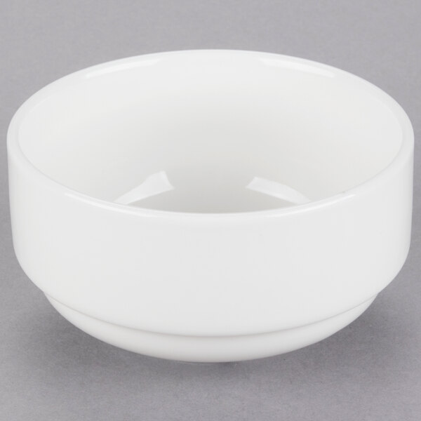 A close up of a Tuxton AlumaTux white soup cup on a gray surface.