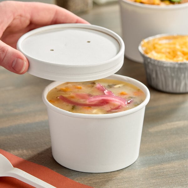 An 8 oz. white paper food cup with a vented paper lid, partially open to reveal soup inside.