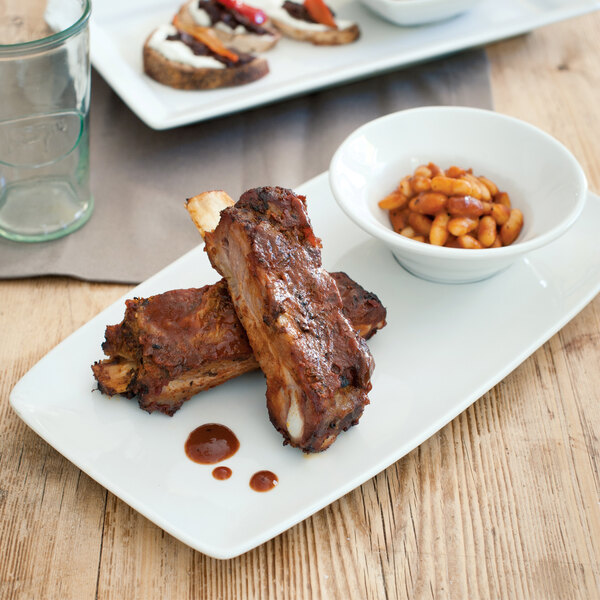 A Tuxton TuxTrendz bright white china bowl with ribs and beans.