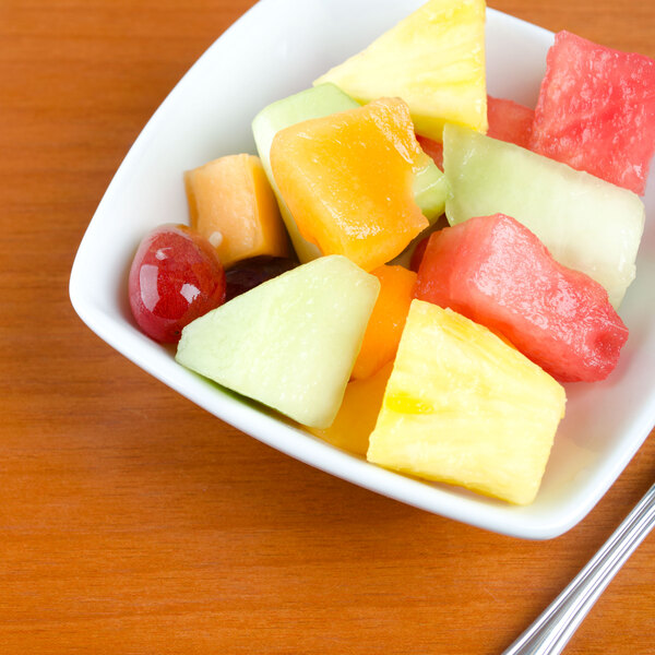 A Tuxton bright white square china bowl filled with fruit on a table.