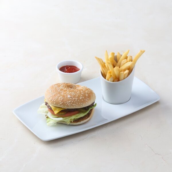 A Tuxton bright white rectangular china tray with a cheeseburger and a cup of french fries.