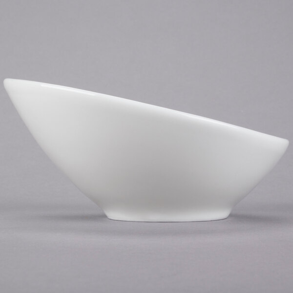 A close-up of a Tuxton bright white china bowl with a curved edge.