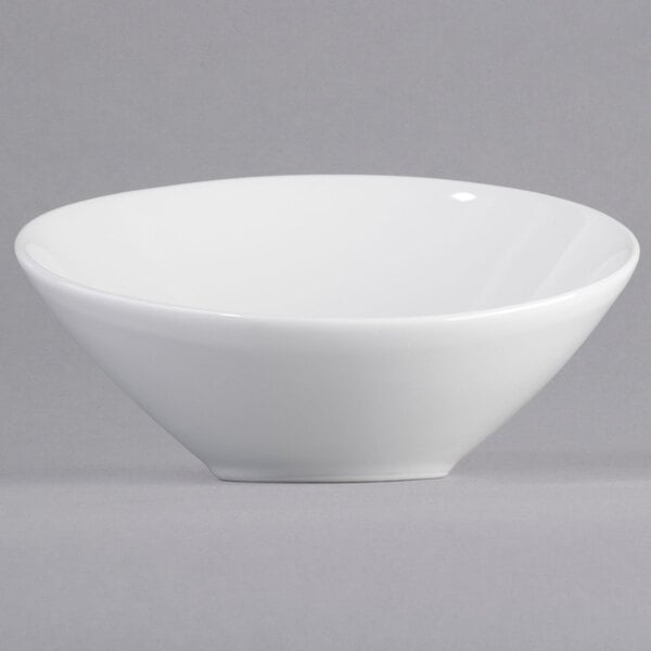 A close-up of a Tuxton bright white china bowl with a small slanted rim.