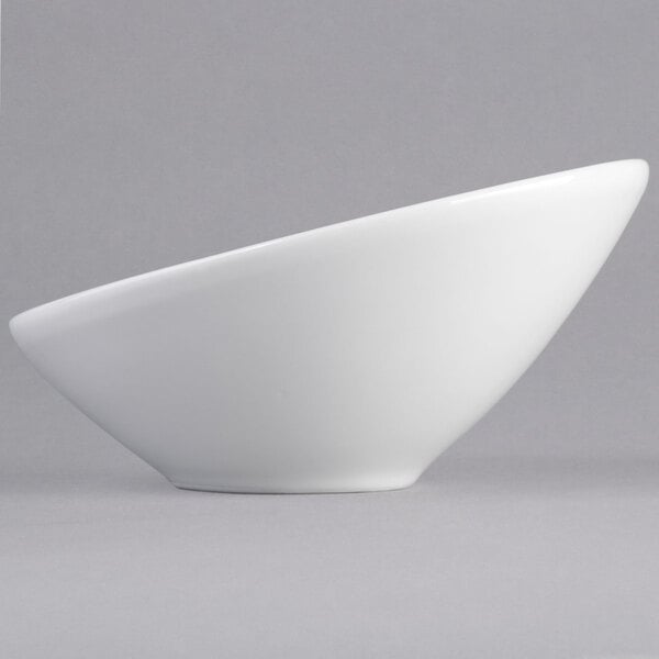 A close-up of a Tuxton bright white china bowl with a curved bottom.