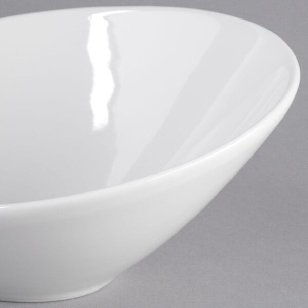A Tuxton TuxTrendz bright white china bowl with a slanted rim.