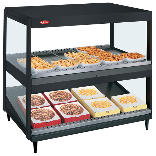 A black Hatco countertop display with food trays and pizza boxes on shelves.
