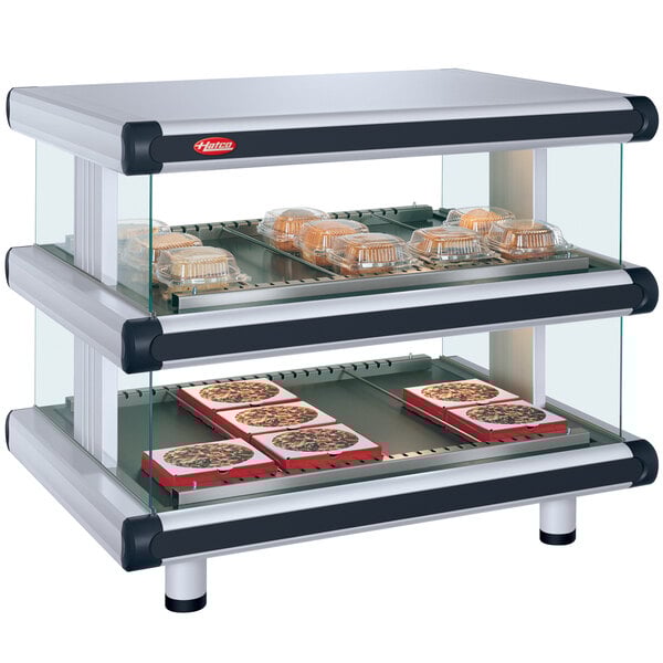 A Hatco white granite countertop merchandiser with food trays on shelves in a glass case.