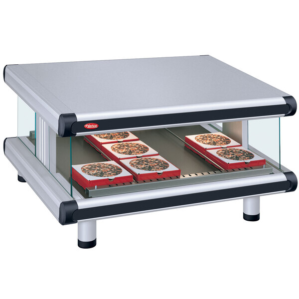 A Hatco countertop food warmer with trays of pizza on a slanted shelf.