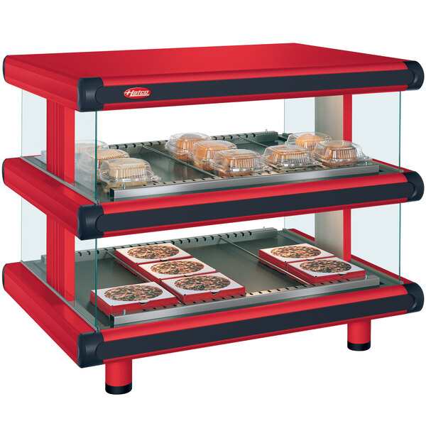 A red and black Hatco countertop food warmer with shelves on a counter in a bakery display.