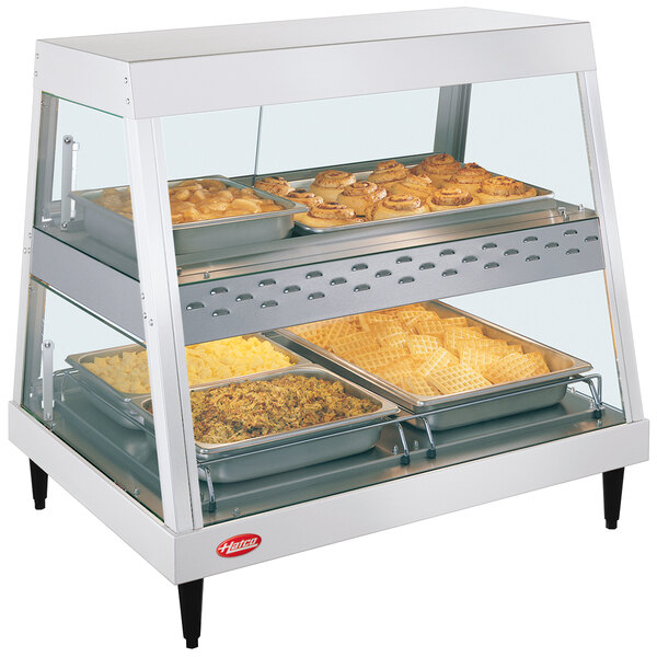 A Hatco countertop hot food display warmer with food on trays in a display case.