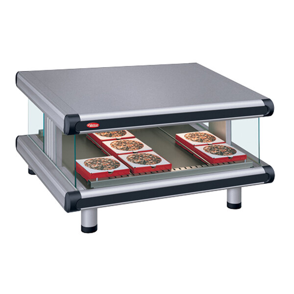 A Hatco countertop food warmer with pizzas on a slanted shelf.