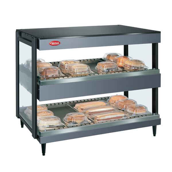 A Hatco Gray Granite double shelf merchandiser with trays of food on a shelf.