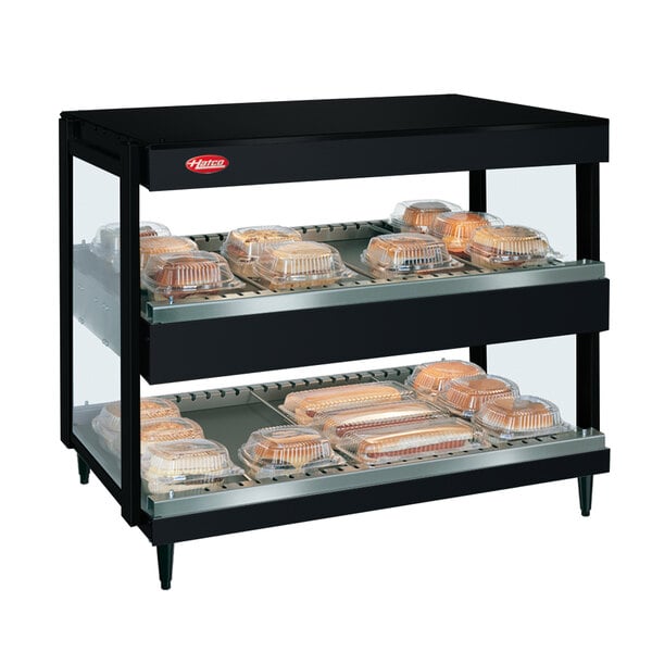 A black Hatco countertop display case with trays of food on shelves.