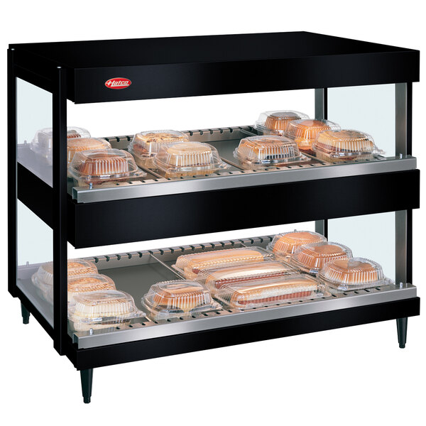 A black Hatco countertop display case with food trays on shelves.