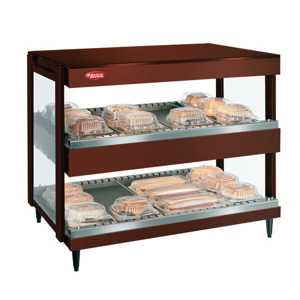 A Hatco horizontal double shelf merchandiser with trays of food on a shelf.