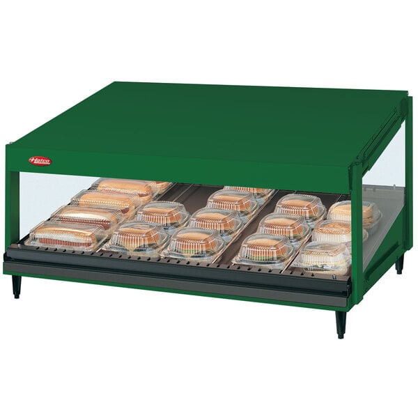 A Hatco Hunter Green countertop display warmer with food on a shelf.