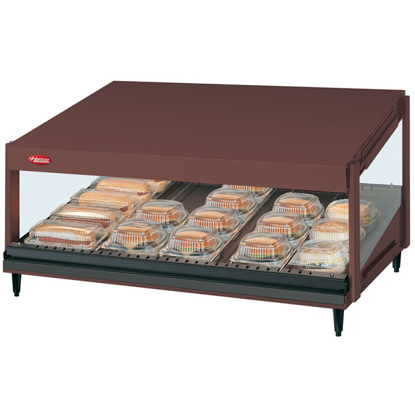 A Hatco countertop food warmer with trays of food on a slanted shelf.