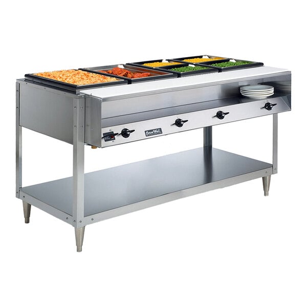 A stainless steel electric four pan hot food table with a lower shelf and plates, designed for serving hot food in a commercial setting.