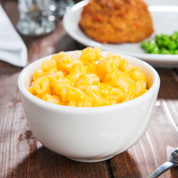 A Tuxton Pearl White china bowl filled with macaroni and cheese with peas.